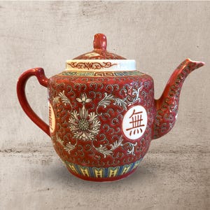 Peut inclure: Théière en céramique rouge avec couvercle et anse. La théière présente un motif floral avec des accents blancs et des caractères chinois. Le bec et la anse sont incurvés. La base a une bordure jaune et bleue.