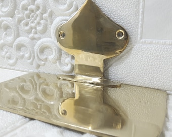 May include: A gold-colored metal soap dish with a decorative, pointed top. The dish is designed to hold a bar of soap.