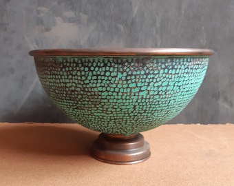 May include: A large, copper bowl with a green, textured finish. The bowl has a wide, round base and a flared lip.