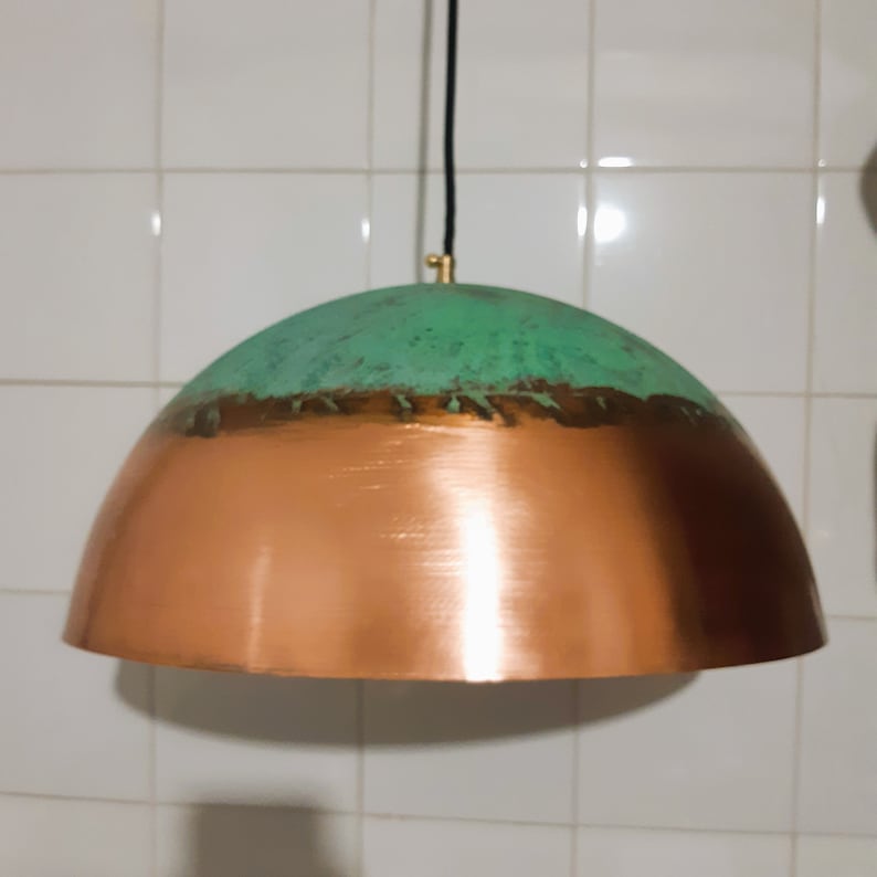 May include: A copper and green pendant light fixture with a dome-shaped shade. The top half of the shade is a distressed green color, and the bottom half is a shiny copper color.