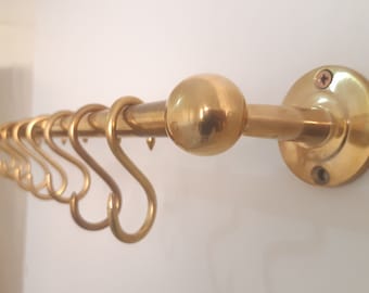 May include: A gold-toned metal wall-mounted coat rack with a round finial and multiple hooks.