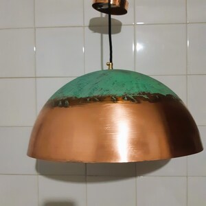 May include: A copper and green pendant light fixture with a dome-shaped shade. The top half of the shade is a distressed green color, while the bottom half is a shiny copper color.