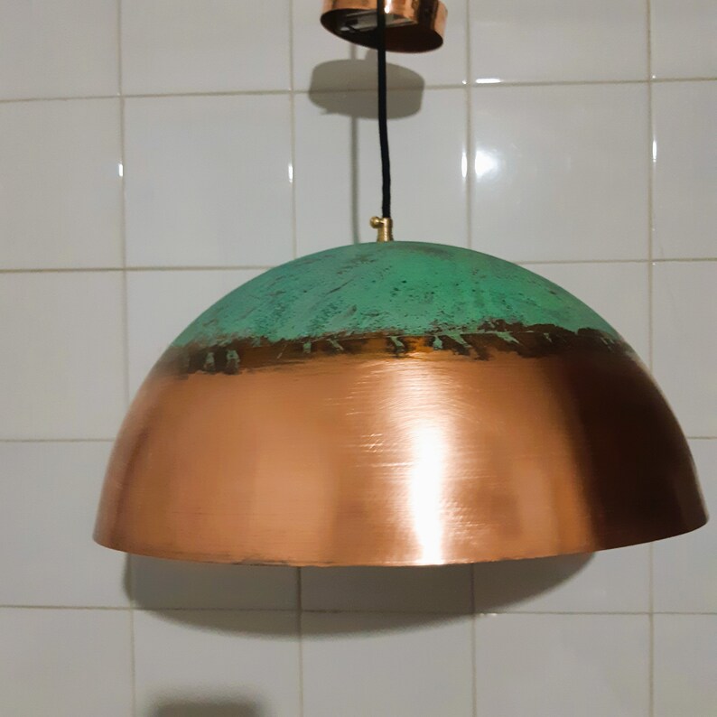 May include: A copper and green pendant light fixture with a dome-shaped shade. The top half of the shade is a distressed green color, while the bottom half is a shiny copper color.