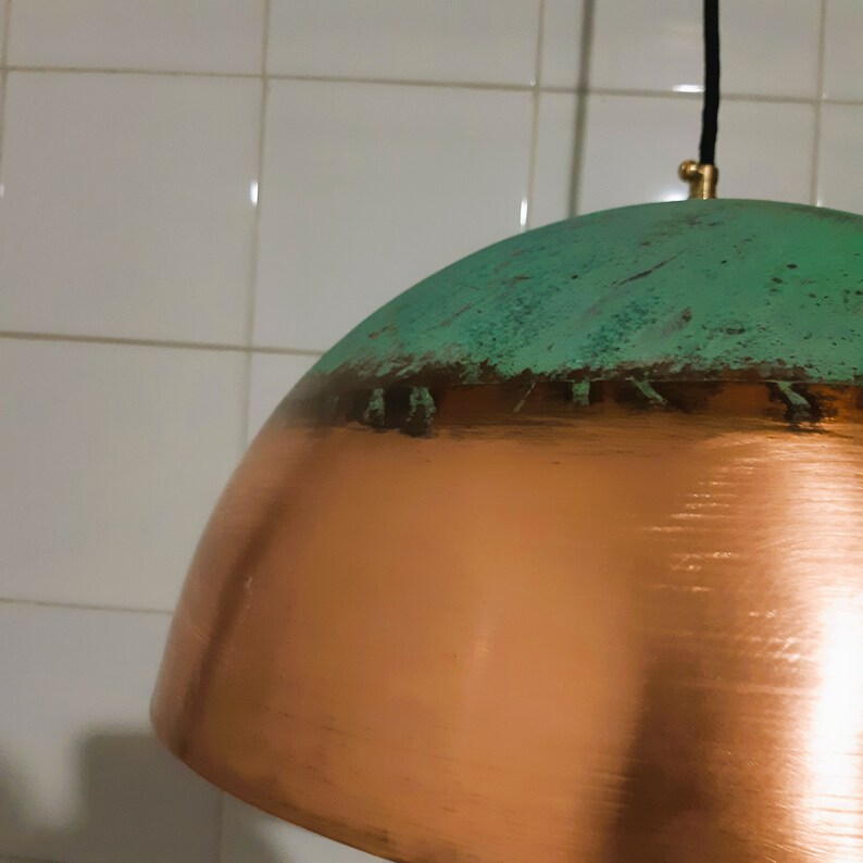 May include: A copper and green pendant light fixture with a dome-shaped shade. The top of the shade is green with a copper band around the edge. The bottom of the shade is copper.