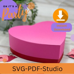 Pode incluir: Uma caixa em forma de cora&ccedil;&atilde;o rosa e vermelha com uma tampa. A caixa &eacute; feita de papel e tem um acabamento liso. O texto "OH IT'S A Party" &eacute; vis&iacute;vel no canto superior esquerdo da imagem. O texto "SVG-PDF-Studio" &eacute; vis&iacute;vel no centro inferior da imagem.