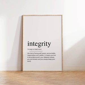 May include: A framed print with the word "integrity" in a bold, black font. The definition of integrity is below the word. The frame is a light wood color, and the background is white. The print is displayed on a wooden floor.