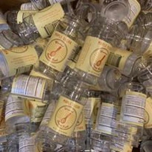 May include: A pile of clear plastic bottles with yellow labels. The labels feature a red spoon and the text "Whole Milk" and "The Spoonful of Love".