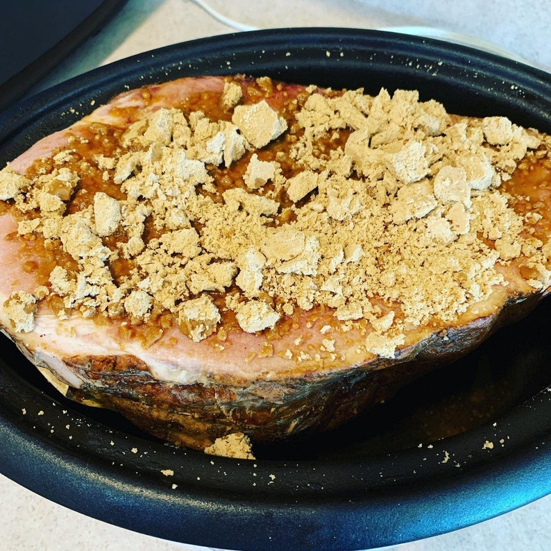 May include: A ham glazed with a brown sugar mixture in a black slow cooker.
