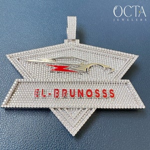 Puede incluir: Un colgante de plata con un dise&ntilde;o engastado en diamantes que presenta un coche estilizado y el texto "EL BRUNOSSS" en letras rojas. El colgante es una pieza llamativa con una est&eacute;tica moderna y lujosa.