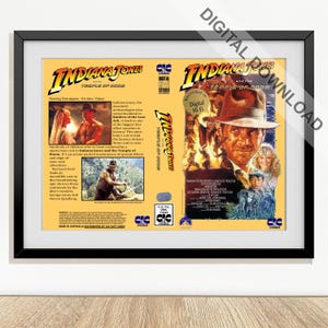 Può includere: Poster incorniciato della copertina della cassetta VHS "Indiana Jones e il tempio maledetto". Il poster presenta il titolo del film in un carattere giallo in grassetto, con immagini di Harrison Ford nei panni di Indiana Jones. Il poster è in una cornice nera.