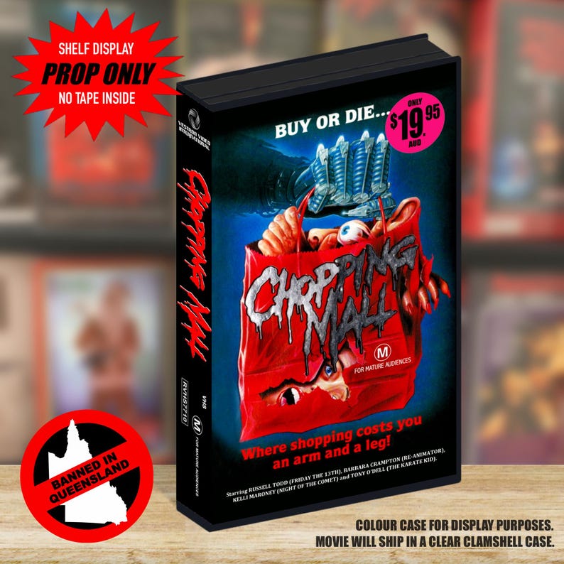 May include: A black VHS case for the film Chopping Mall featuring a red shopping bag with a clawed hand and eyes on the cover. The text reads Buy or Die, Chopping Mall, and Where shopping costs you an arm and a leg. It includes a pink price sticker.
