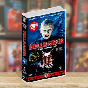 May include: A VHS tape of the horror film "Hellraiser." The cover features a blue background with the film's title in red and the tagline "He'll tear your soul apart." The image of the character Pinhead is prominently displayed.