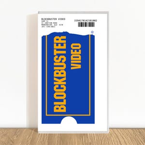 May include: A white Blockbuster Video rental card with a blue and yellow logo. The card has the Blockbuster Video logo in large yellow letters on a blue background. The card also includes the store address and a barcode.