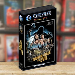 Peut inclure: Une cassette VHS noire pour le film Tucker & Dale vs. Evil. La jaquette montre deux hommes en casquette, une cabane, un camion et une grande silhouette sombre tenant une hache. Le texte inclut K-Tel Video, Filmways VTC et le titre en jaune.