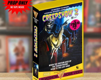 Może przedstawiać: Żółte etui VHS na film Creepshow 2 z wizerunkiem szkieletu w fotelu kinowym. Okładka zawiera tekst The Masters of the Macabre, Stephen King i George A. Romero oraz hasło When the curtain goes up the terror begins.