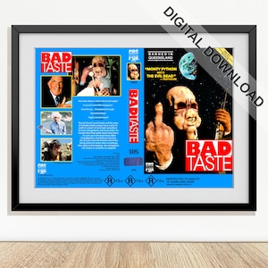 Könnte beinhalten: Ein gerahmter Druck des VHS-Covers für den Film "Bad Taste". Das Cover hat einen blauen Hintergrund mit Bildern von Charakteren und dem Filmtitel in Rot und Weiß. Das Bild enthält den Text "Banned in Queensland".