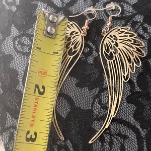 Puede incluir: Pendientes de alas de &aacute;ngel de tono dorado con cierre de gancho. Los pendientes miden aproximadamente 5 cm de largo.