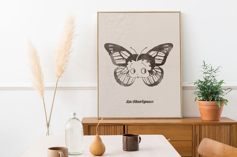 May include: A black and white illustration of a butterfly with a cartoon face. The butterfly is on a beige background with the text "La Mariposa" printed below it.
