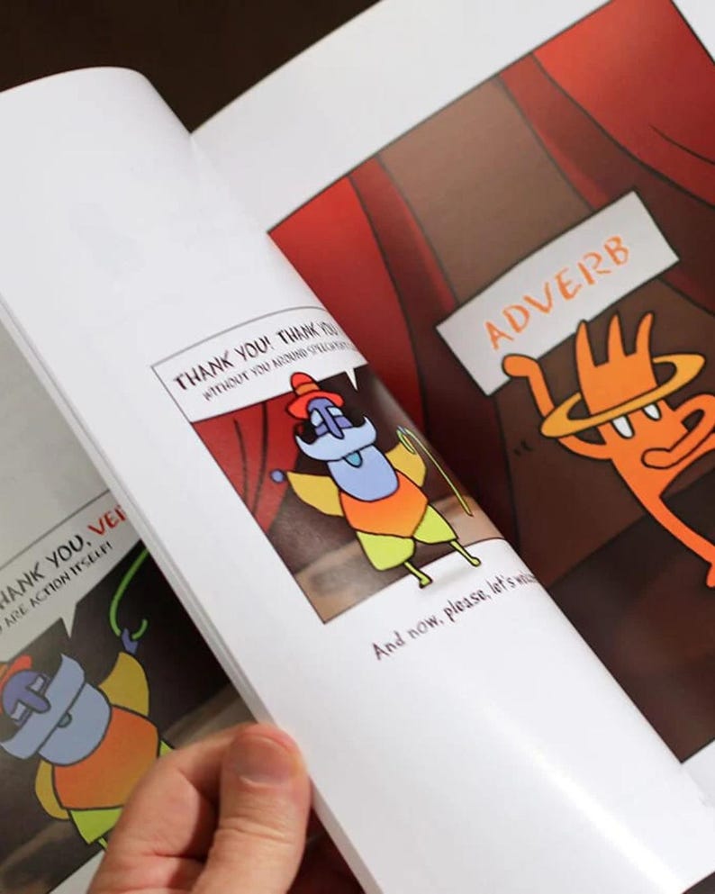 A hand flipping through The Language Theater book, showing a colorful adverb character on a stage-themed page with bold illustrations.
