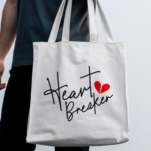 May include: White canvas tote bag with black script text that reads "Heart Breaker" and a red broken heart graphic.