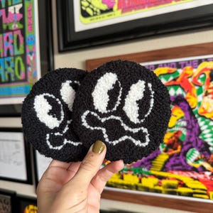 May include: Two black and white fuzzy round coasters with a skull and crossbones design.