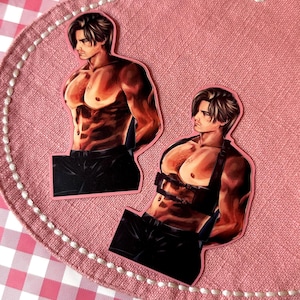 May include: Two stickers featuring a muscular, shirtless figure with dark hair and black pants. One sticker has the figure with arms behind the back, the other has a harness. The stickers are on a pink background.