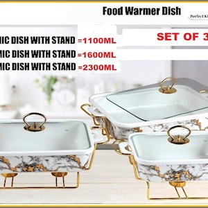 May include: Set of three white ceramic food warmer dishes with gold accents and glass lids. The dishes are on gold metal stands. 11" dish = 1100ml, 13" dish = 1600ml, 15" dish = 2300ml. Set of 3.
