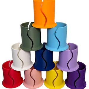 May include: A set of ten colorful plastic cup holders. The holders are stacked in a pyramid shape. The colors are orange, green, blue, white, navy blue, purple, red, pink, yellow, and purple.