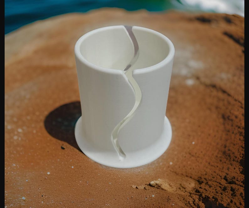 Op de afbeelding: Een witte keramische garenkom met een gladde, matte afwerking en een brede, ronde basis. De kom heeft een enkele, doorlopende verticale opening die van de bovenrand naar de basis buigt, ontworpen voor het vasthouden en afgeven van garen.