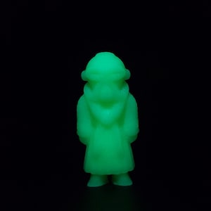 May include: A glowing green figurine of a robed figure with a hood, standing against a black background. The figure has a simple, stylized design, with a long robe and a hooded head covering. The figurine is illuminated, creating a bright, eye-catching effect.