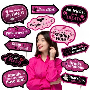 May include: A collection of Halloween-themed photo booth props in various shapes, including speech bubbles and arrows. The props feature phrases like "Boo-tiful," "No tricks, just TREATS," and "That's my ghoul!" in pink and black with glitter accents.