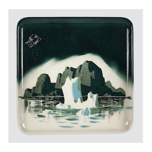 May include: A square ceramic tray with a green border and a white interior. The tray features a painted scene of a rocky island with a waterfall and icebergs in the water. The artist's signature, "Mall" is visible in the upper left corner.