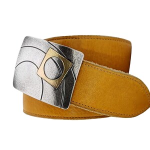 May include: Mustard yellow leather belt with a silver and gold-toned buckle. The buckle features a square gold accent and a silver design with curved lines. The belt is a medium width and has a classic design.
