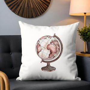 May include: White throw pillow featuring a watercolor illustration of a globe. The globe has a blush pink color scheme with a leopard print base and accents. The pillow is on a dark gray chair.