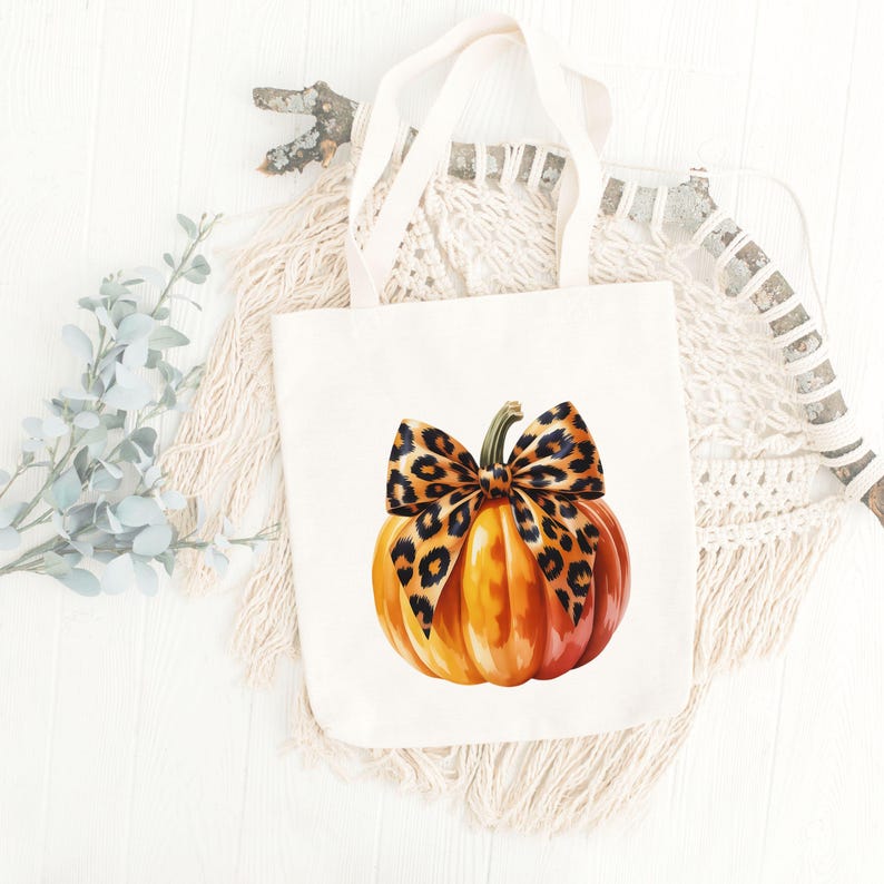 Pode incluir: Uma sacola creme com uma ab&oacute;bora em aquarela com um la&ccedil;o com estampa de leopardo. A ab&oacute;bora &eacute; laranja e vermelha com uma haste verde. A sacola tem duas al&ccedil;as creme.