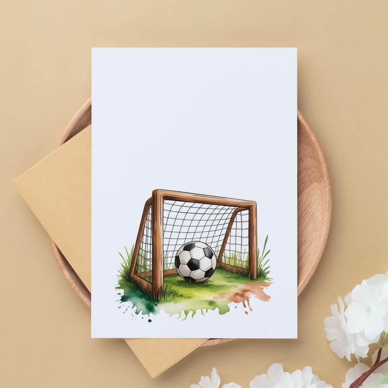 May include: A watercolor illustration of a soccer ball in a goal on a greeting card. The goal is brown with a white net, set on green grass with colorful paint splatters. The card is on a wooden plate with an envelope.
