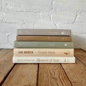 May include: A stack of five books with different coloured covers. The top book is titled "Daughter Mine" by Robert Gold. The second book is titled "The Full Cupboard of Life" by Alexander McCall Smith. The third book is titled "Netherland" by Joseph O'Neill. The fourth book is titled "Lorne Rubenstein x Touring Prose". The bottom book is titled "Elements of Style" by Wendy Wasserstein.