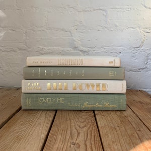 May include: A stack of five books with green and white covers. The top book is white with gold lettering that reads "REGENERATION" by Pat Barker. The second book is green with gold lettering that reads "Don't Let's Be Silly" by  Morris West. The third book is white with gold lettering that reads "REEL POWER" by  John D. MacDonald. The fourth book is green with gold lettering that reads "LOVELY ME" by  Jacqueline Susann. The bottom book is green with gold lettering that reads "The Life of Jacqueline Susann".