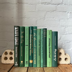 May include: A collection of 12 green hardback books with gold lettering on the spines. The books are arranged in a row on a wooden surface. The books are all different sizes and have different titles. The titles include "Knife Edge", "The After Party", "Spring and Fall", "The Disciplined Trader", "Leo Burner Star Reacher", "Call Me Tomorrow", "Charlie Farquharson's History of Canada", "All Creatures Great and Small", and "Going in my own way".
