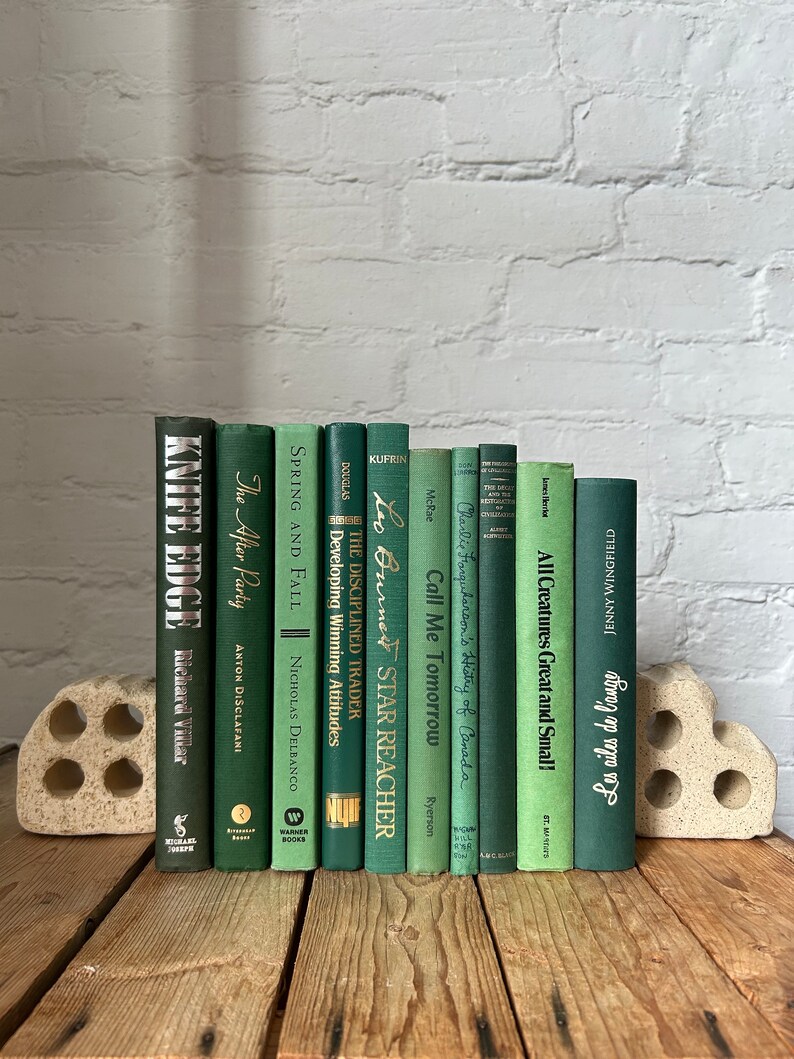 May include: A collection of 12 green hardback books with gold lettering on the spines. The books are arranged in a row on a wooden surface. The books are all different sizes and have different titles. The titles include "Knife Edge", "The After Party", "Spring and Fall", "The Disciplined Trader", "Leo Burner Star Reacher", "Call Me Tomorrow", "Charlie Farquharson's History of Canada", "All Creatures Great and Small", and "Going in my own way".