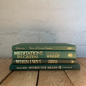 May include: A stack of four green hardback books with gold lettering. The titles are "Hero of Lesser Causes", "Meditations in Green", "When I Was", and "Within Our Means".
