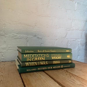May include: A stack of four green hardback books with gold lettering on the spines. The titles are "Hero of Lesser Causes", "Meditations in Green", "When I Was", and "Within Our Means".