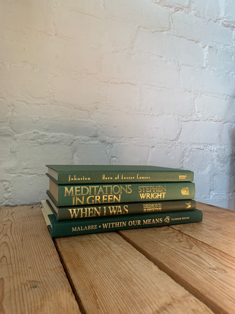 May include: A stack of four green hardback books with gold lettering on the spines. The titles are "Hero of Lesser Causes", "Meditations in Green", "When I Was", and "Within Our Means".