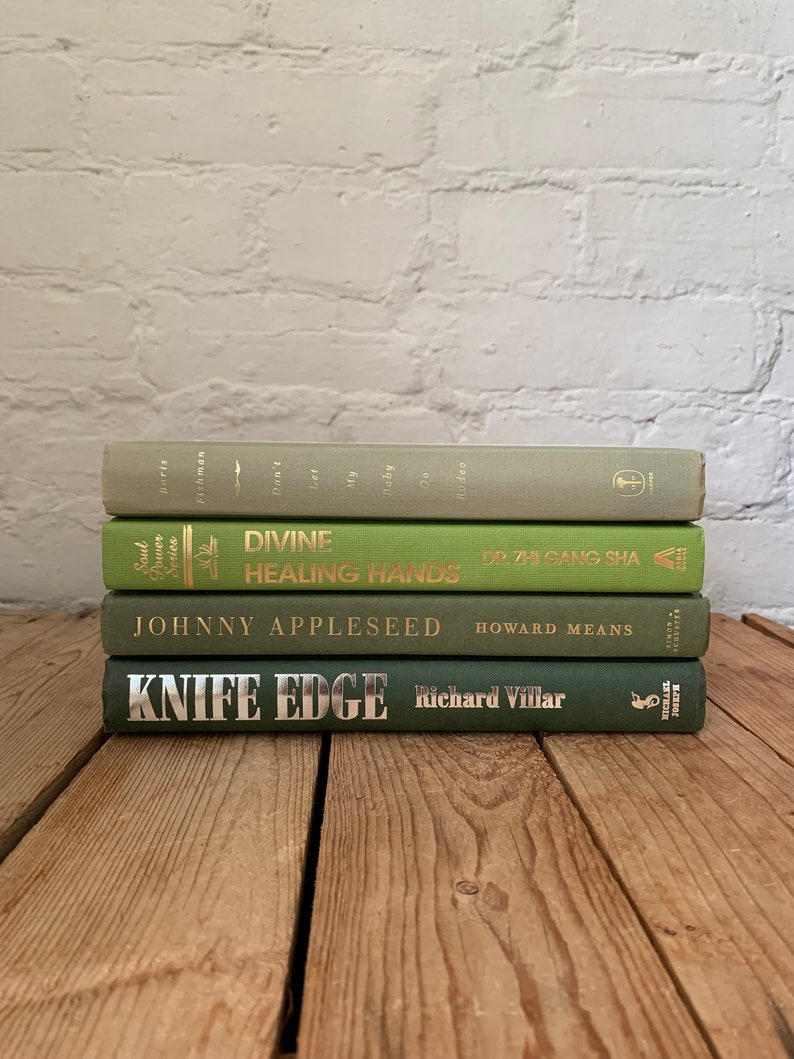 May include: A stack of four green hardback books with gold lettering. The titles are "Don't Let My Baby Do Rodeo", "Divine Healing Hands", "Johnny Appleseed", and "Knife Edge".