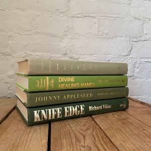 May include: A stack of four green hardback books with gold lettering. The titles are "Divine Healing Hands", "Johnny Appleseed", "Knife Edge", and "Don't Let My Baby Do That To Me".