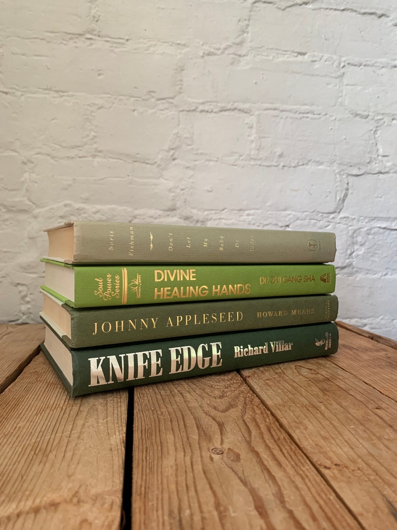 May include: A stack of four green hardback books with gold lettering. The titles are "Divine Healing Hands", "Johnny Appleseed", "Knife Edge", and "Don't Let My Baby Do That To Me".