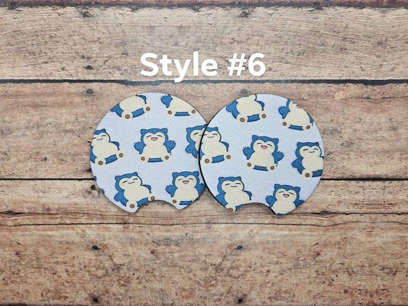May include: Two white round drink coasters with a blue and white cartoon character design. The coasters feature a cartoon character with a blue body and a white face. The text "Style #6" is printed above the coasters.
