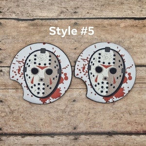 May include: Two car coasters featuring a white mask with black eye holes, a red triangle mouth, and red blood splatter. The text "Style #5" is above the coasters. The coasters are on a wooden surface.