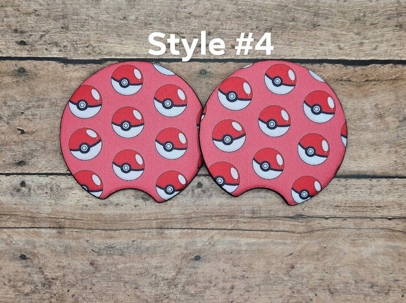 May include: Two red and white patterned drink coasters with a Pokeball design. The coasters are shaped like a car cup holder. Style #4.