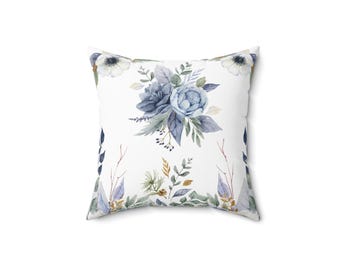 May include: A white throw pillow with a blue and green floral pattern. The flowers are watercolor style and include blue roses and white anemones.